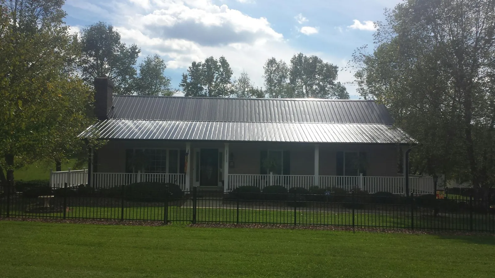 Gray metal roof on a brick ranch with a full width front porch — Gutter Guard Installation work by our crew in Smithfield